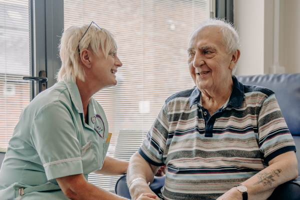 1 Femal healthcare profiessional smiling at 1 elderly male at Ashgate Hospice