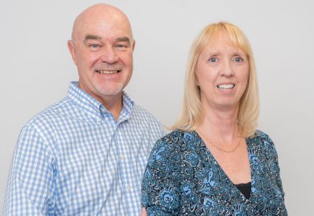 1 male and 1 female smiling at the camera