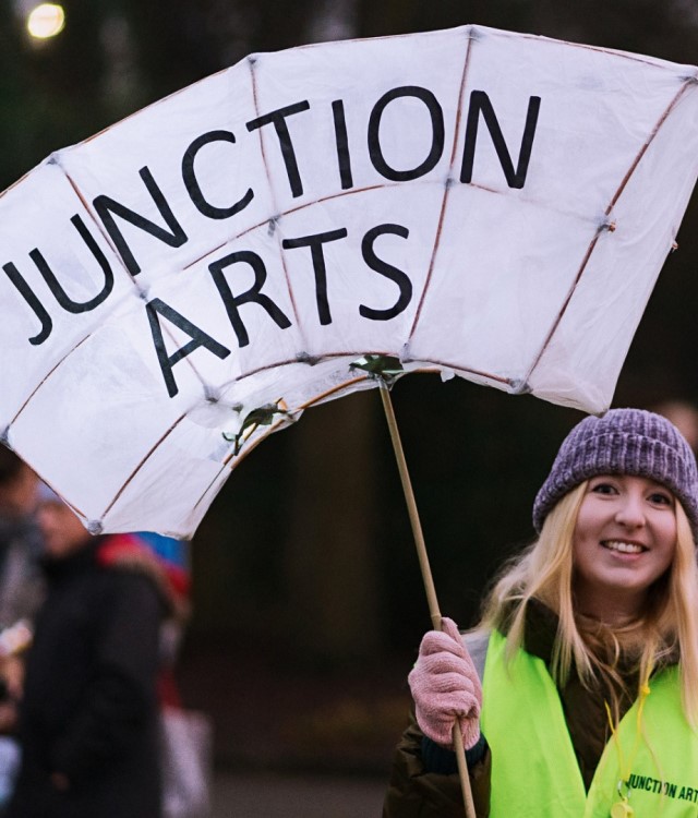 junction arts team member holding up a lantern banner