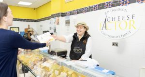 Cheese Factor female team member serving cheese in a paper bag to a female customer