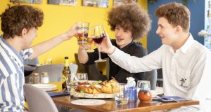 Friends with plates of food at Sicily Restaurant in Chesterfield, clinking glasses to say cheers