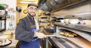 Giuseppe from Sicily Restaurant in apron removing freshly-baked bread from the oven using a flatboarde kitchen