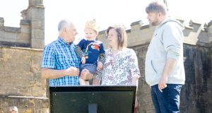 Family with young boy in arms, looking at education board at Bolsover Castle