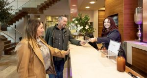Male and female checking in at Casa Hotel, speaking to female receptionist