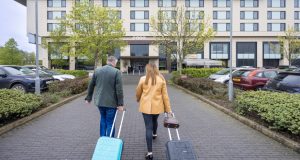 Male and female pulling suitcases walking towards Casa Hotel