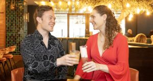 Young male in black shirt toasting champagne with a young female dressed in red