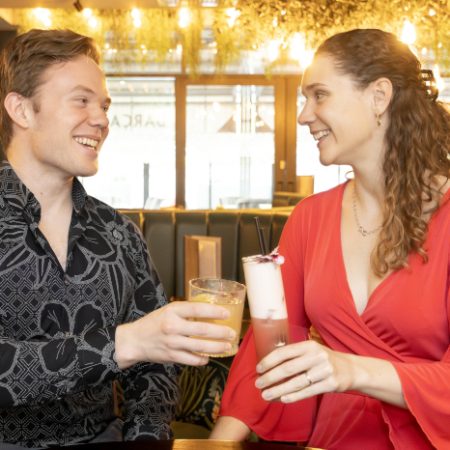 Young male in black shirt toasting champagne with a young female dressed in red
