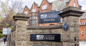 Branded stone wall in front of red brick building - University of Derby Chesterfield campus