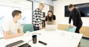 A female and 3 male business people in discussion around a laptop at BHP, 1 Waterside Place, Chesterfield