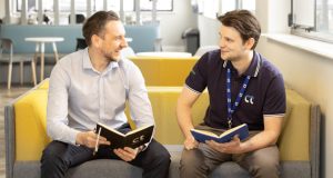 Two white males having a meeting on yellow sofa, notebooks in hand at Central Technology, Dunston