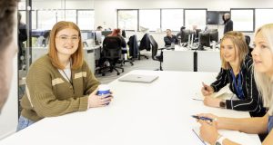 Three female business people at white table at Central Technology, Dunston, office of people in background