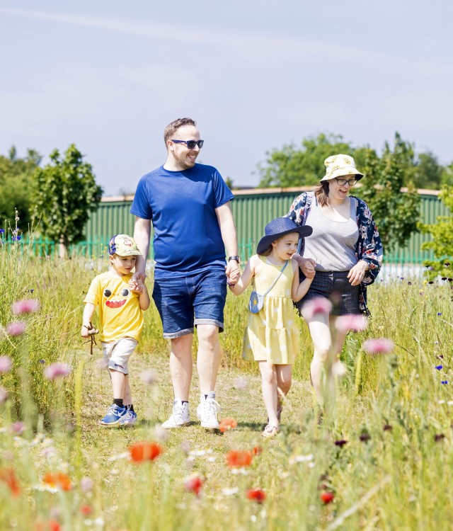 Family walking on a path in Queens Park looking at flowers
