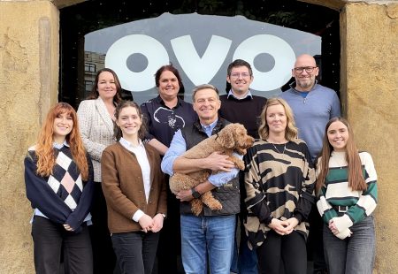 Group of 9 people and a cockapoo dog outside of ovo spaces