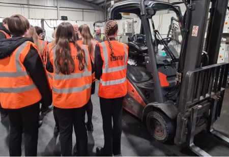 Group of students in high vis jackets in a warehouse