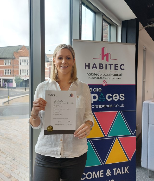 Woman wearing white shirt holding certificate and smiling for camera